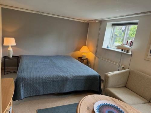 a bedroom with a bed and a chair and a window at Herning midtby in Herning