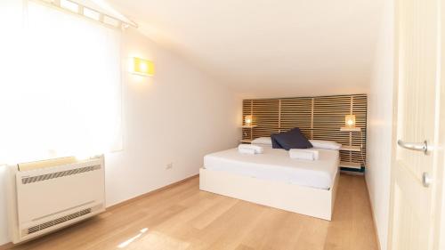 a white bedroom with a bed and a window at Villa Marina-S'Arena Scoada by Sardinianworld in Putzu Idu