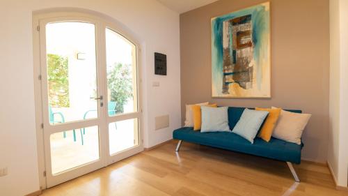 a living room with a blue couch and an open door at Villa Marina-S'Arena Scoada by Sardinianworld in Putzu Idu