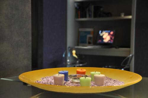 a yellow bowl with candles on a glass table at Rome Airport Hotel Fiumicino in Fiumicino