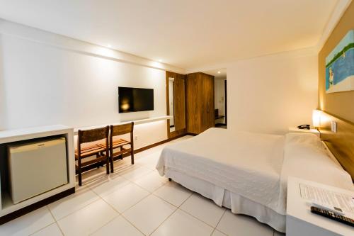 a hotel room with a bed and a flat screen tv at Porto Suítes Natal Hotel in Natal