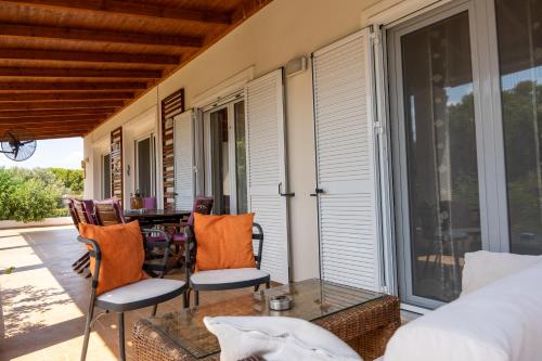 a screened porch with a glass table and chairs at Beautiful Summer Villa in Chalkoutsi in Khalkoútsion