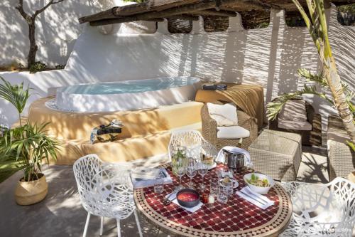 a patio with a table and chairs and a hot tub at Hacienda Na Xamena, Ibiza in Na Xamena