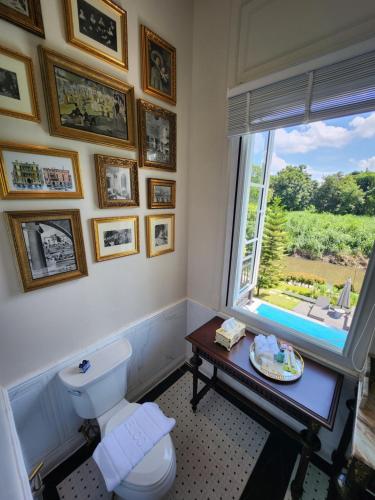 a bathroom with a toilet and a window and a table at La Campagne Villa Chiangmai in Chiang Mai