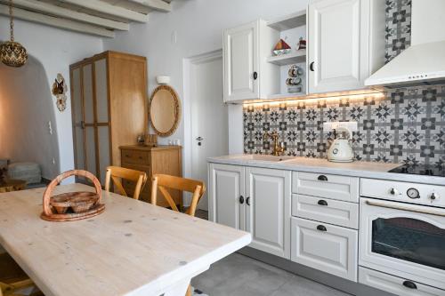 a kitchen with white cabinets and a wooden table at Fisherman's Syrma House in Pachaina