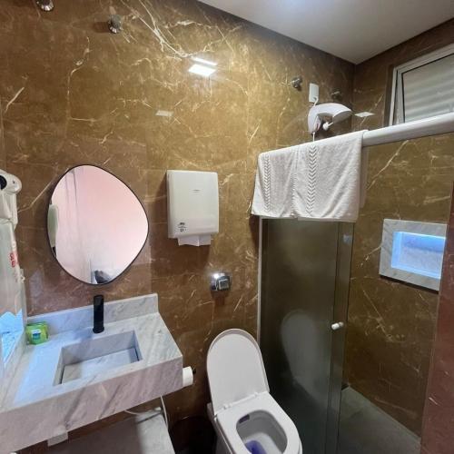 a bathroom with a toilet and a sink and a mirror at Motel Drive in T - Prolongamento da Avenida Getúlio Vargas fácil acesso ao Shopping Pátio Chapecó in Chapecó