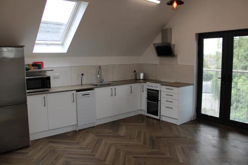 a kitchen with white cabinets and a wooden floor at White House apartment, Staines upon Thames in Staines upon Thames