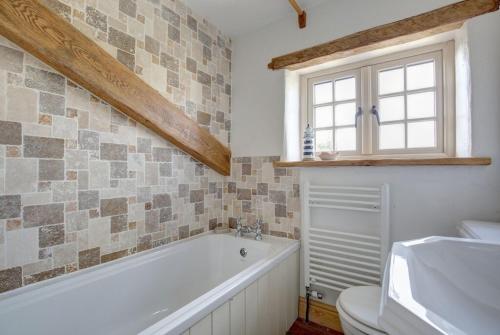 une salle de bain avec une baignoire, des toilettes et un lavabo dans l'établissement Sloe Gin Cottage, à Heacham