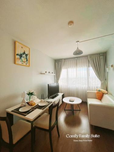 a living room with a table and a living room with a couch at 2BR Comfy Family Suite Hat Yai in Hat Yai