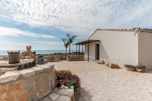 a white building with a patio with the ocean in the background at Mangiabove in Marina di Ragusa