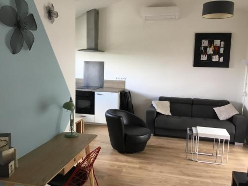 un salon avec un canapé noir et une table dans l'établissement Maison 2ch, Parking, à 10min de Bx, Calme, à Mérignac