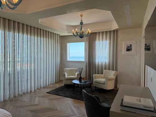 a living room with chairs and a table and a large window at Grand Hotel Gallia in Milano Marittima
