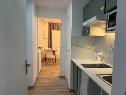 a kitchen with white counters and a hallway with a table at Le Royal, proche Paris & Disney in Noisy-le-Grand