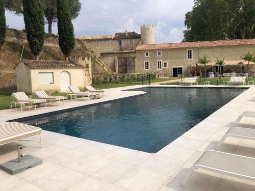 a swimming pool with chairs and a building at Château de Taulignan in Saint-Marcellin-lès-Vaison