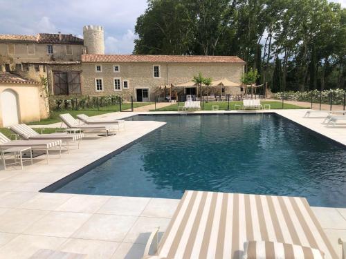 a swimming pool in front of a house with chairs at Château de Taulignan in Saint-Marcellin-lès-Vaison