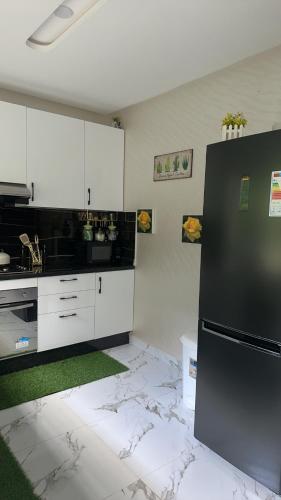 a kitchen with a black refrigerator and white cabinets at Superbe appartement de luxe- proche de la mer - Dahomey city - Bouznika in Bouznika