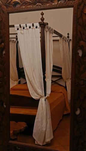 a mirror in a bedroom with a bed with curtains at Donnaciccina Accomodation in Tropea