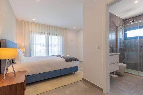 a bedroom with a bed and a bathroom with a shower at Luxuosa Villa Baía in Alfeizerão