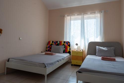 a bedroom with two beds and a window at Beautiful Summer Villa in Chalkoutsi in Khalkoútsion