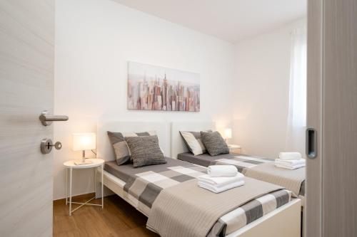 two beds in a white room with a door at Apartment SarAna Trogir in Trogir