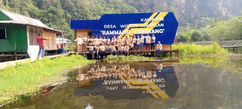 a group of people standing on a dock in the water at Desa Wisata Rammang-rammang in Baloci