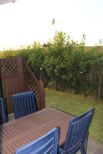 a wooden table and two blue chairs on a patio at Ferienwohnung Martje vom Deich, Kalifornien, erste Strandreihe in Schönberg