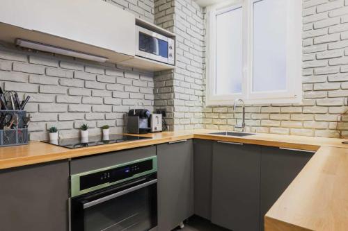 une cuisine avec un évier et une cuisinière four supérieur dans l'établissement Modern flat - 1BD-4P - Parc Monceau, à Paris