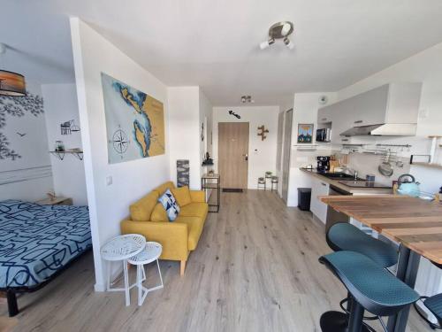 - un salon et une cuisine avec un canapé jaune dans la chambre dans l'établissement Les Carrelets - Jardin d'Hiver- WIFI-TERRASSE-PAKING, à Puilboreau
