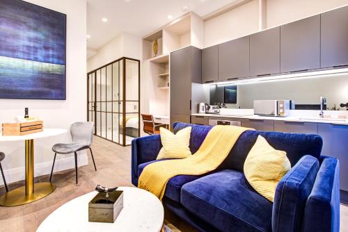 a living room with a blue couch and a kitchen at Luxury Apartments near Canary Wharf in London