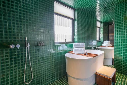 a green tiled bathroom with a tub and a sink at Jiangnan House Nantou in Shenzhen