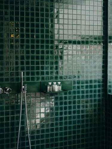 a green tiled wall in a bathroom with toilets at Jiangnan House Nantou in Shenzhen
