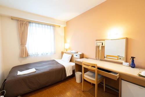 Cette chambre comprend un lit et un bureau avec un miroir. dans l'établissement Sapporo Clark Hotel, à Sapporo