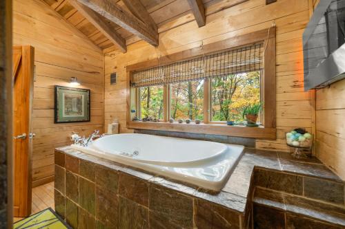 La grande salle de bains est pourvue d'une baignoire et d'une fenêtre. dans l'établissement Cabin Porch Paradises, à Unionville