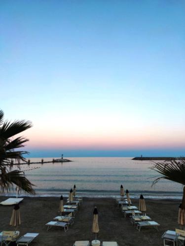 una spiaggia con sedie a sdraio e l'oceano al tramonto di Renesmee Beach Apartment a Pietra Ligure