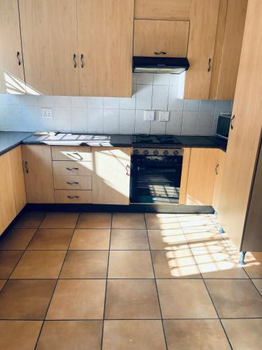 a kitchen with wooden cabinets and a tiled floor at Golden Glory Manor in Roodepoort
