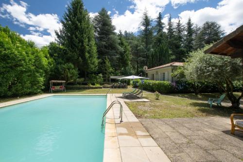 a large swimming pool in a yard with trees at Magnifique Maison Paisible avec Piscine in Jaujac
