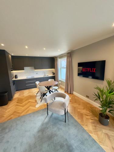a living room with a table and chairs and a kitchen at Macbeths Corner - Luxury Apartment with Private Parking in Stratford-upon-Avon