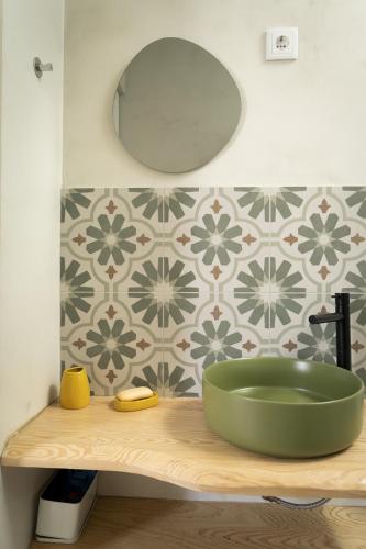 a bathroom sink with a green bowl on a wooden counter at B&B Casa Areia in Colares