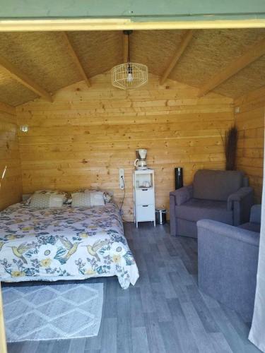 - une chambre avec un lit et un canapé dans une cabine dans l'établissement Camping La sablière, à Saint-Jans-Cappel