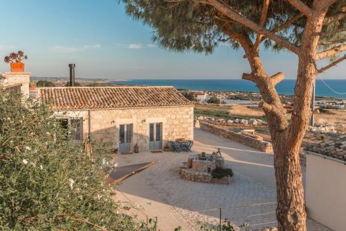 a house with a tree in front of a street at Mangiabove in Marina di Ragusa