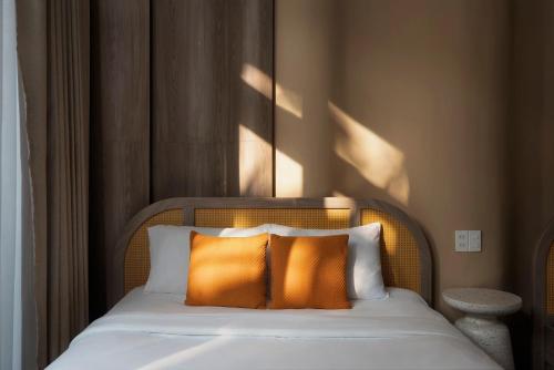 a bed with two orange pillows in a room at The Palette Dalat in Da Lat