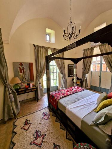 a bedroom with a canopy bed and a chandelier at LA PORTE AU LION - Marrakech in Marrakesh