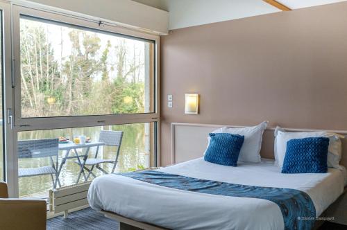 a bedroom with a bed and a large window at Hôtel L'ile Du Saussay in Itteville