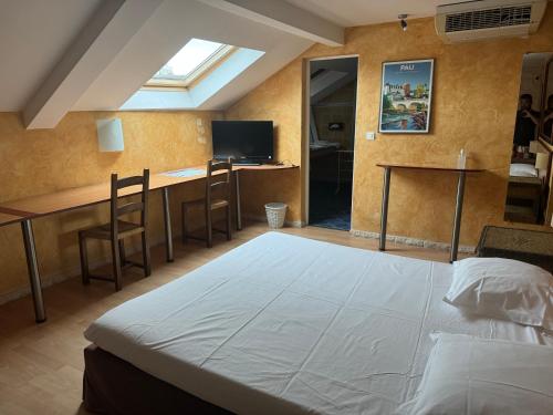 a bedroom with a bed and a desk and a television at Hôtel Bosquet Pau Centre - Self Check In Budget Hotel in Pau