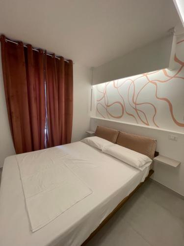 a small bedroom with a white bed with a window at Residenza Leonina in San Martino in Pensilis