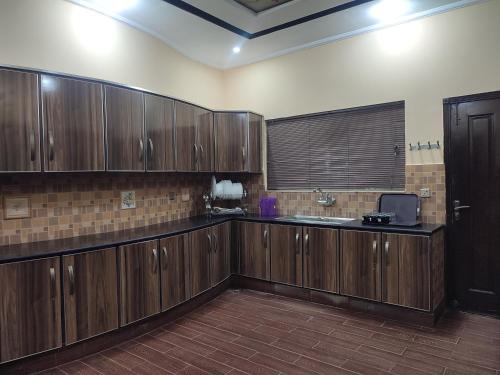 a large kitchen with wooden cabinets and a sink at Fully Serviced Holiday Homes Near Emporium Mall & Expo Center in Lahore