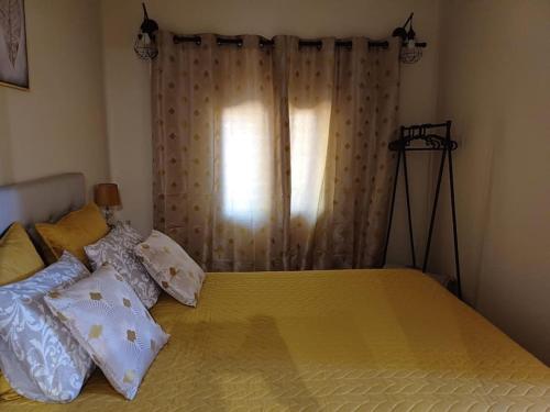 a bedroom with a yellow bed with pillows and a window at Casa Vó Elisa com piscina privada in São Bartolomeu de Messines