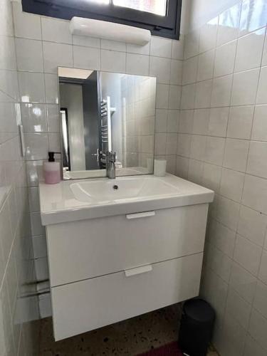 une salle de bain blanche avec un lavabo et un miroir dans l'établissement Maison 2 chambres 3 lits 4 couchages et extérieur, à Villefranche-de-Lauragais