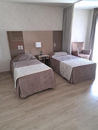 une chambre d'hôtel avec deux lits et une chaise dans l'établissement ZENAO MONTREUIL- Croix de Chavaux, à Montreuil