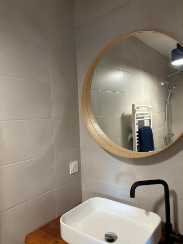 une salle de bain avec un lavabo blanc et un miroir dans l'établissement Maison en bois Lacanau centre, à Lacanau